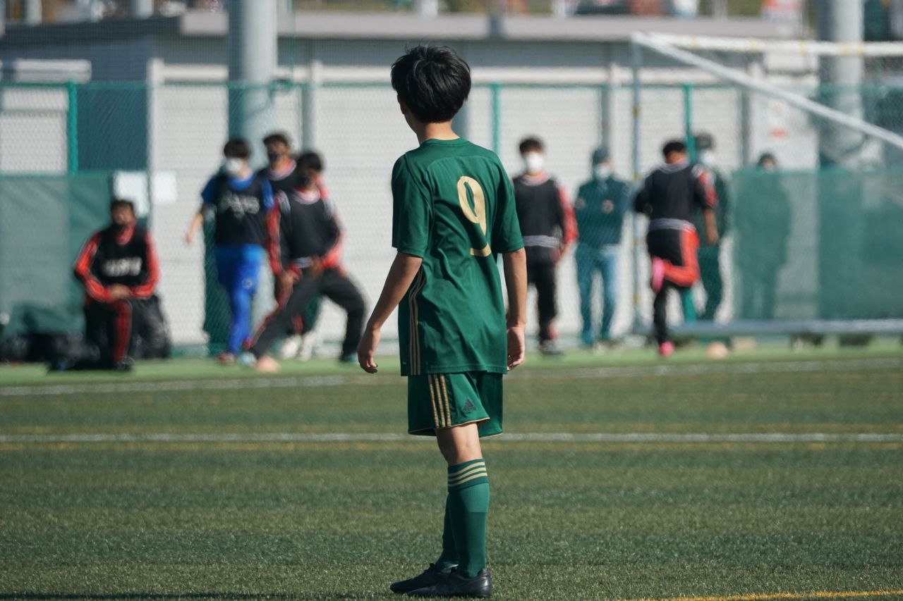 services-02 Youth soccer player in green jersey on football field during match.